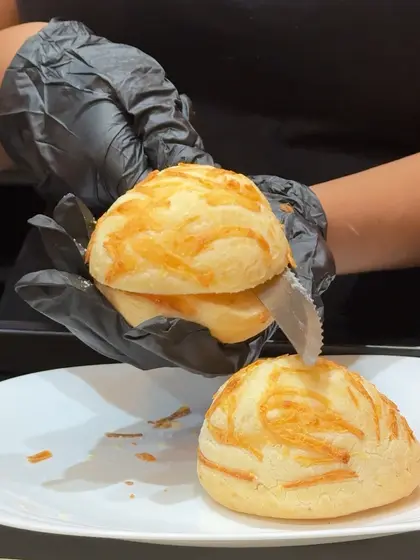 Preparo do pão de queijo sendo cortado, mostrando a casca dourada